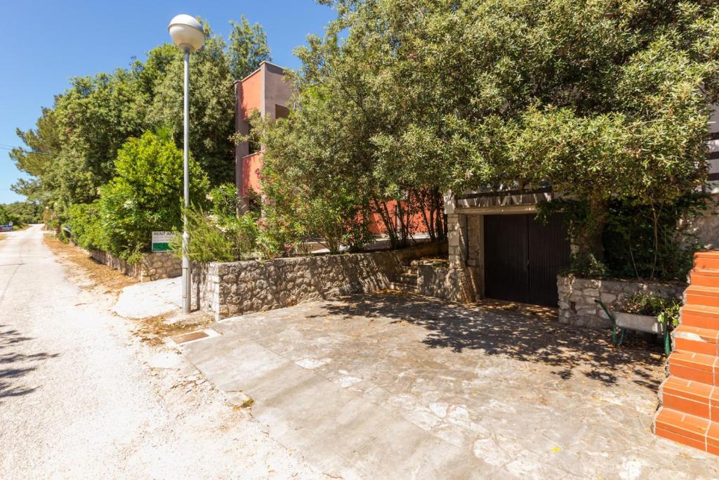 a street with a tree and a garage at Apartments Nives, Artatore in Mali Lošinj