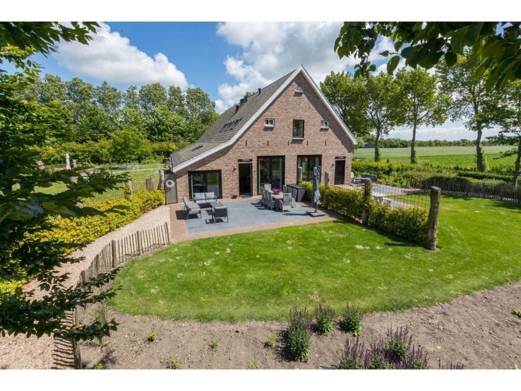 a stone house with a patio and grass at Very luxurious holiday home in beautiful Zeeland style suitable for 7 people in Vrouwenpolder