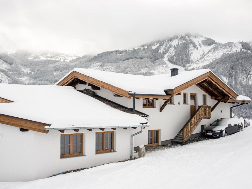 a house covered in snow with a car parked in front at Apartment in Kaprun near the ski area in Kaprun