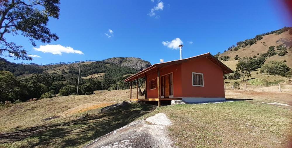 a small red house on top of a hill at Chalé Flor de ypê in Sapucaí-Mirim