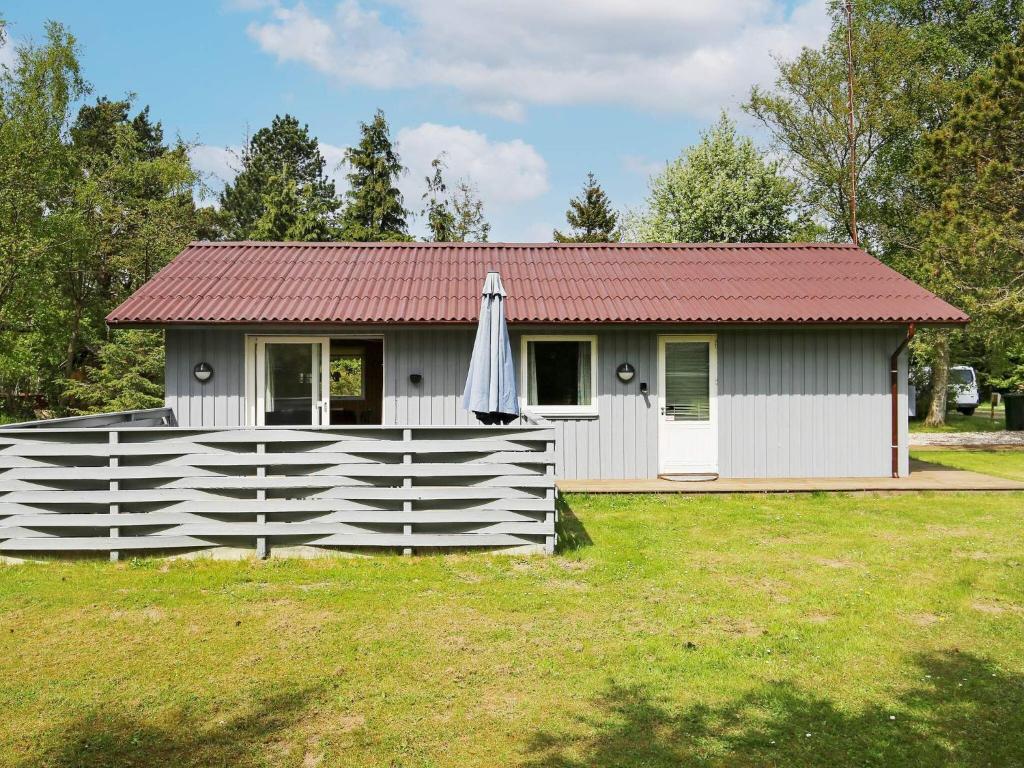 una pequeña casa con una valla blanca y una sombrilla en Holiday home Gedser VIII, en Gedser