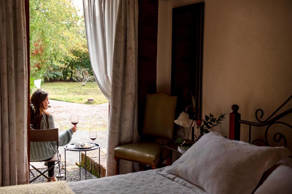 a woman sitting at a table with a glass of wine at Hotel Boutique Solaz Bella Vista de Colchagua in Santa Cruz