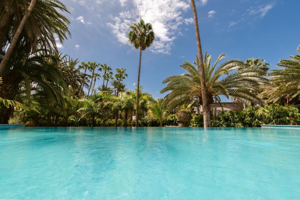 una grande piscina con palme sullo sfondo di Eden Meloneras by TAM Resorts a Maspalomas