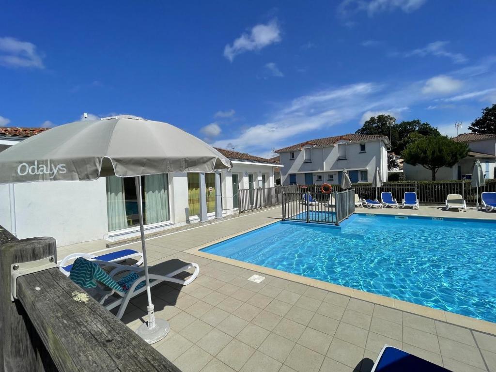 un parasol et des chaises à côté d'une piscine dans l'établissement Maisonnette 4 pers avec terrasse privée et accès piscine, proche océan - Saint-Brevin-les-Pins - FR-1-364-102, à Saint-Brévin-les-Pins