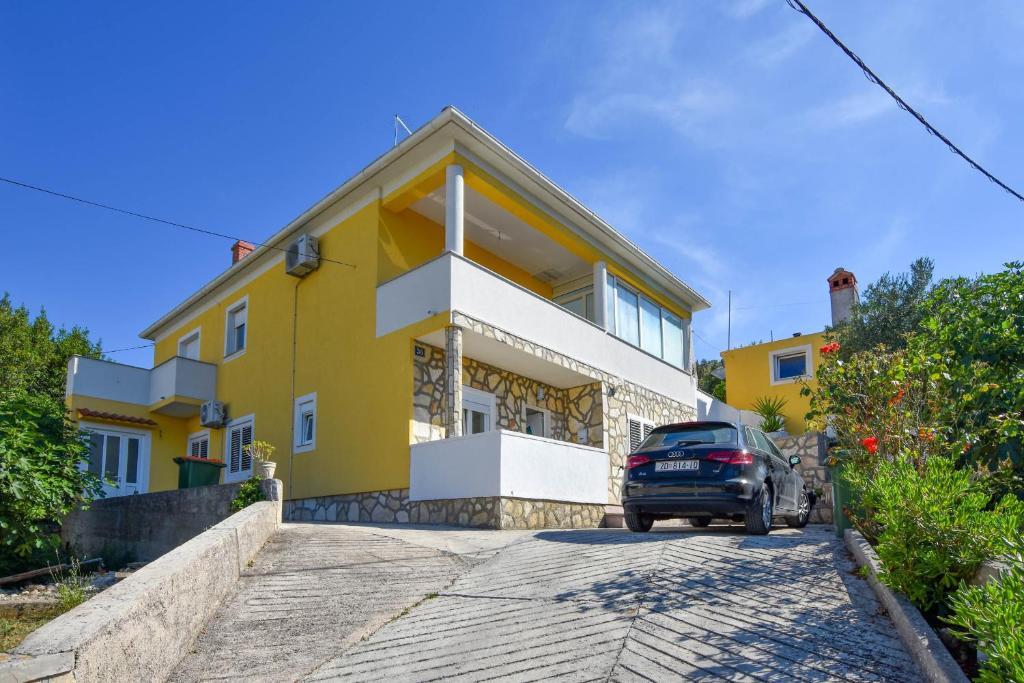 samochód zaparkowany przed żółtym domem w obiekcie Apartment S and E w mieście Kali