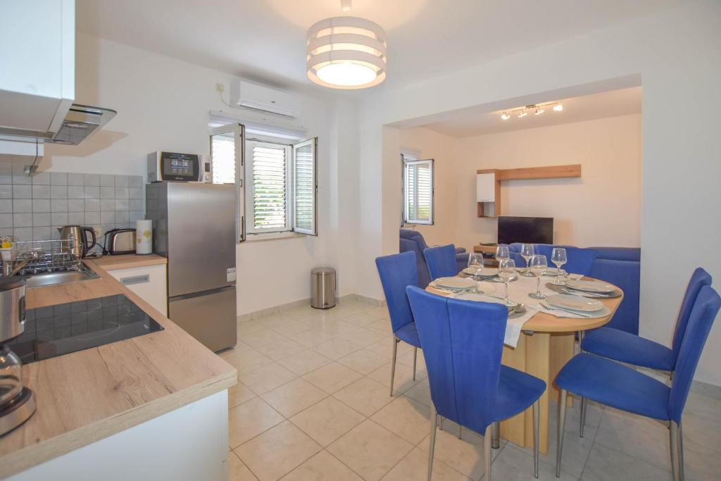 kuchnia i jadalnia ze stołem i niebieskimi krzesłami w obiekcie Apartment S and E w mieście Kali