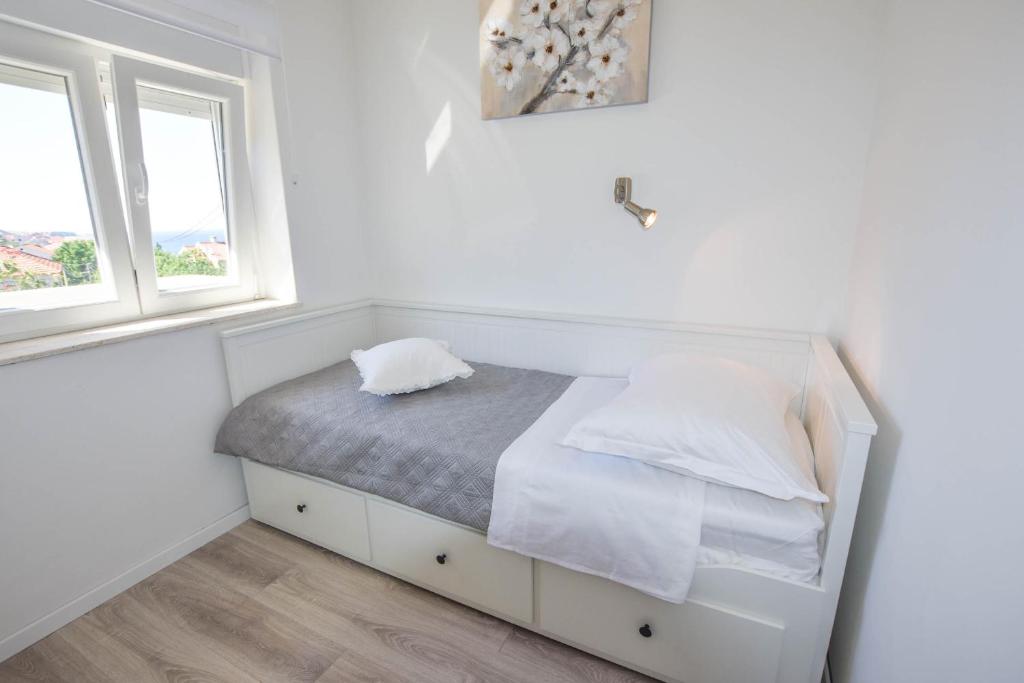 łóżko w białym pokoju z 2 oknami w obiekcie Apartment S and E w mieście Kali
