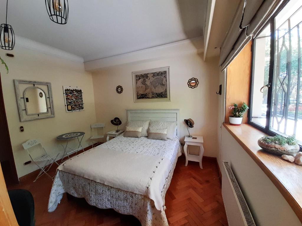 1 dormitorio con cama, mesa y ventanas en Bed & Breakfast Lastarria, en Santiago