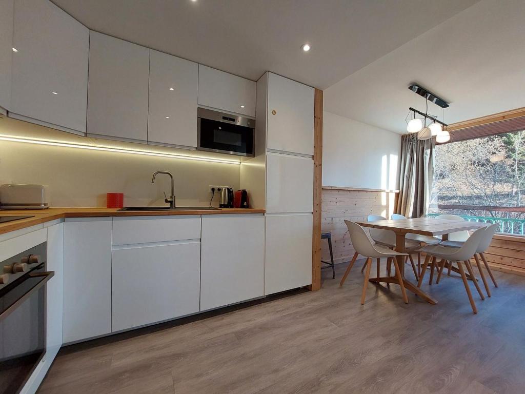 a kitchen with white cabinets and a table with chairs at Appartement Les Arcs 1800, 3 pièces, 7 personnes - FR-1-346-313 in Arc 1800