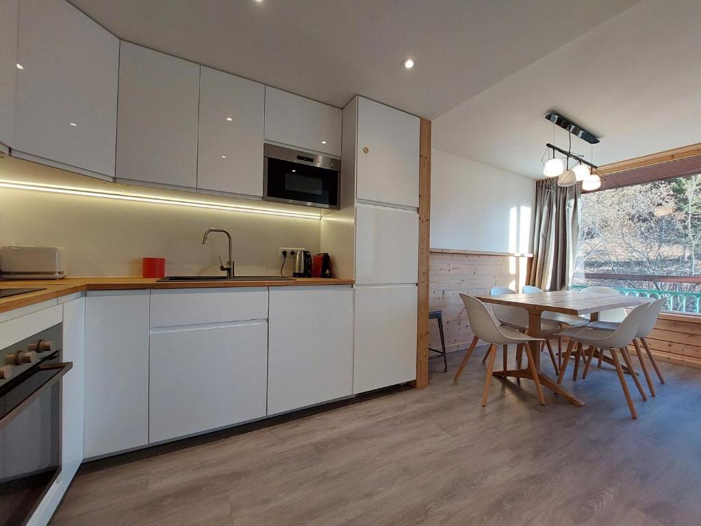 une cuisine avec des armoires blanches et une table avec des chaises dans l'établissement Appartement rénové 7 personnes · Ski aux pieds · Balcon sud · Wifi gratuit - FR-1-346-313, à Arc 1800