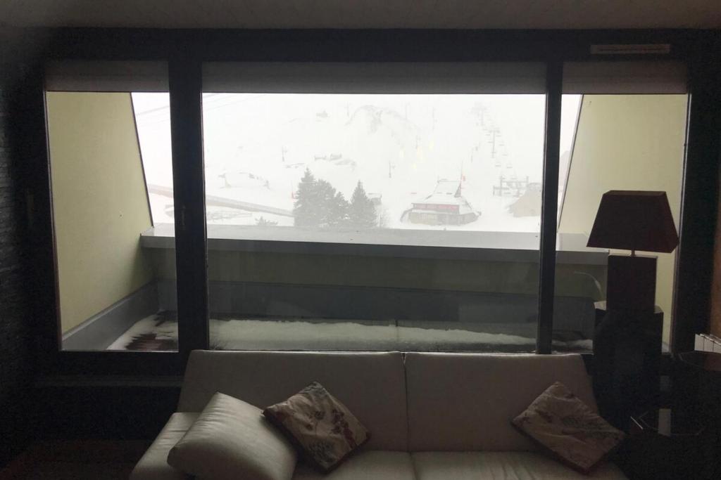 un salon avec un canapé et une grande fenêtre dans l'établissement Appartement "le chamois" Mongie centre 10 pers Bel appartement standing, à La Mongie