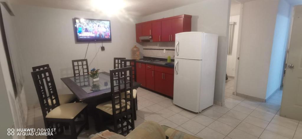 Il comprend une cuisine équipée de placards rouges et d'un réfrigérateur blanc. dans l'établissement Hermoso departamento Casa Lirio (Real Solare), à Querétaro