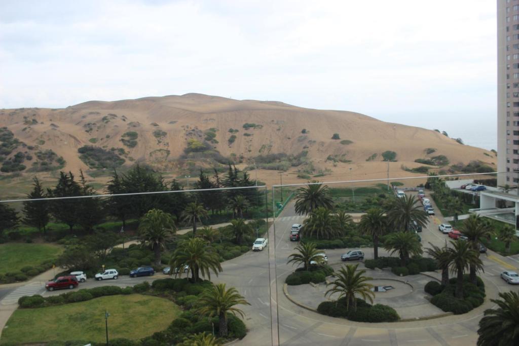 uma vista para um parque de estacionamento com uma montanha ao fundo em Cómodo departamento acceso a dunas de Concón em Concón
