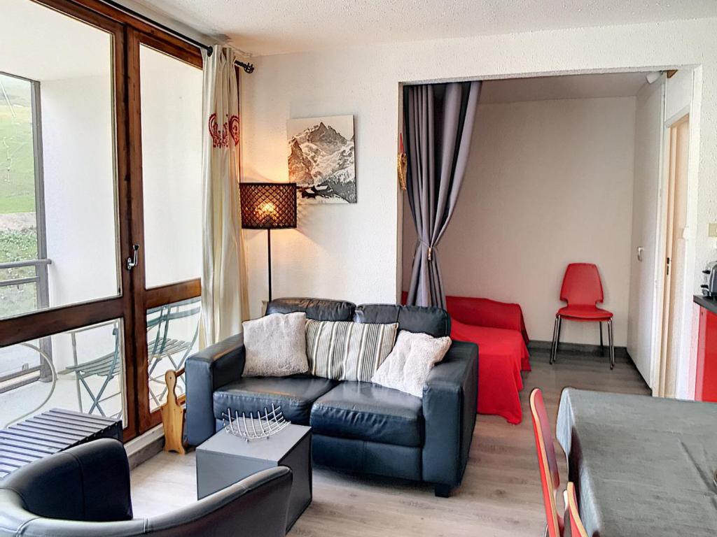 - un salon avec un canapé et un fauteuil rouge dans l'établissement Appartement lumineux en centre station avec balcon et accès piscine - FR-1-267-200, au Corbier