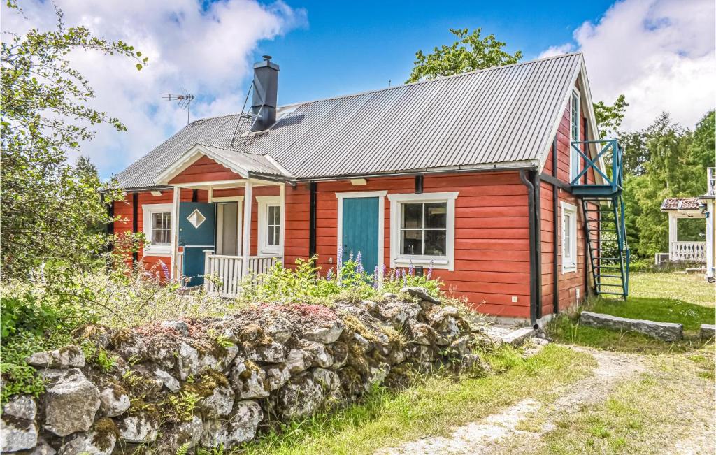 a red cottage with a gray roof and a stone wall at Nice Home In Olofstrm With Kitchen in Olofström