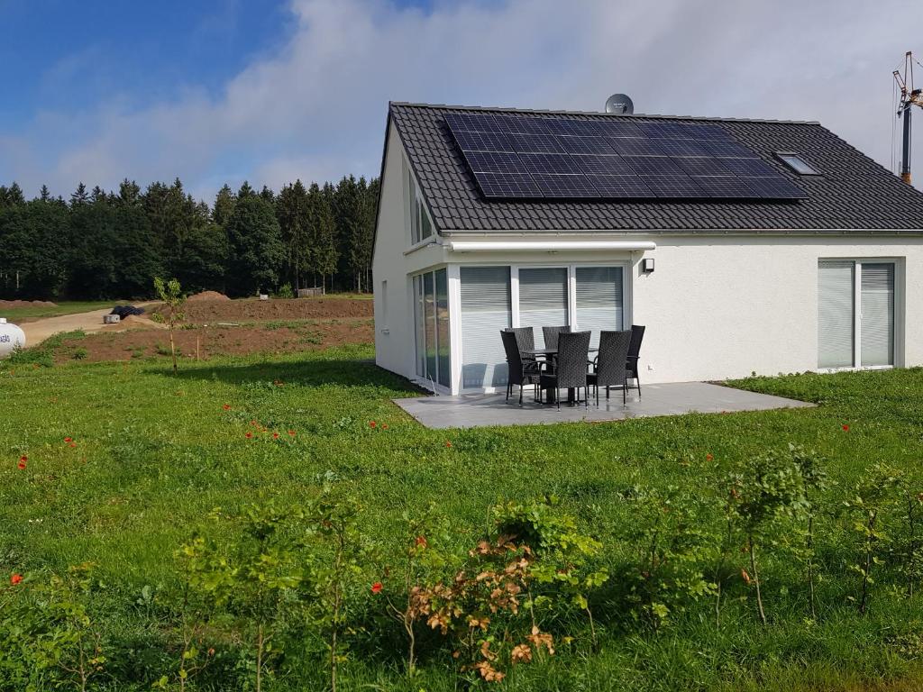 ein Haus mit einer Gruppe von Stühlen und einem Solardach in der Unterkunft Ferienhäuser Prüm in Prüm