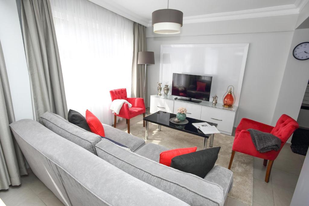 sala de estar con sofá gris y sillas rojas en Patika Suites, en Estambul