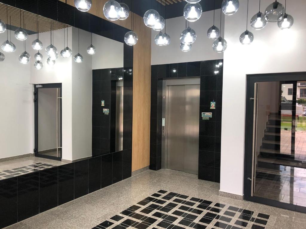 a lobby with black tile and lights on the wall at Apartament Pileckiego in Suwałki