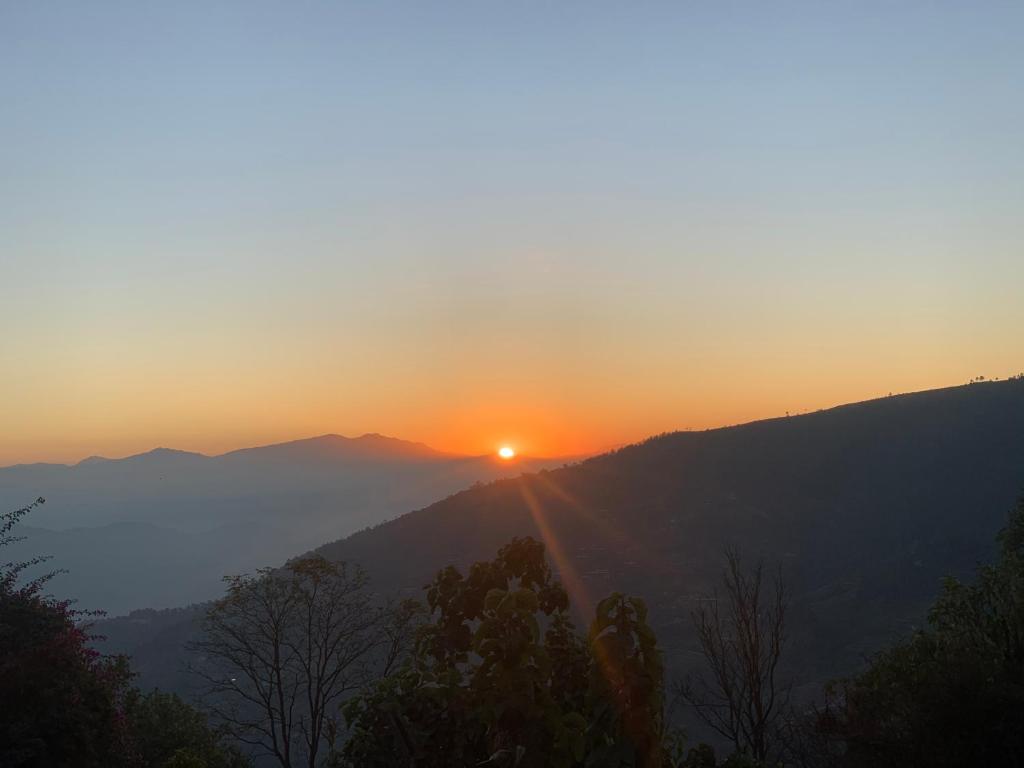 einen Sonnenuntergang in den Bergen mit Sonnenuntergang am Horizont in der Unterkunft Nagarkot Trekkers Inn in Nagarkot
