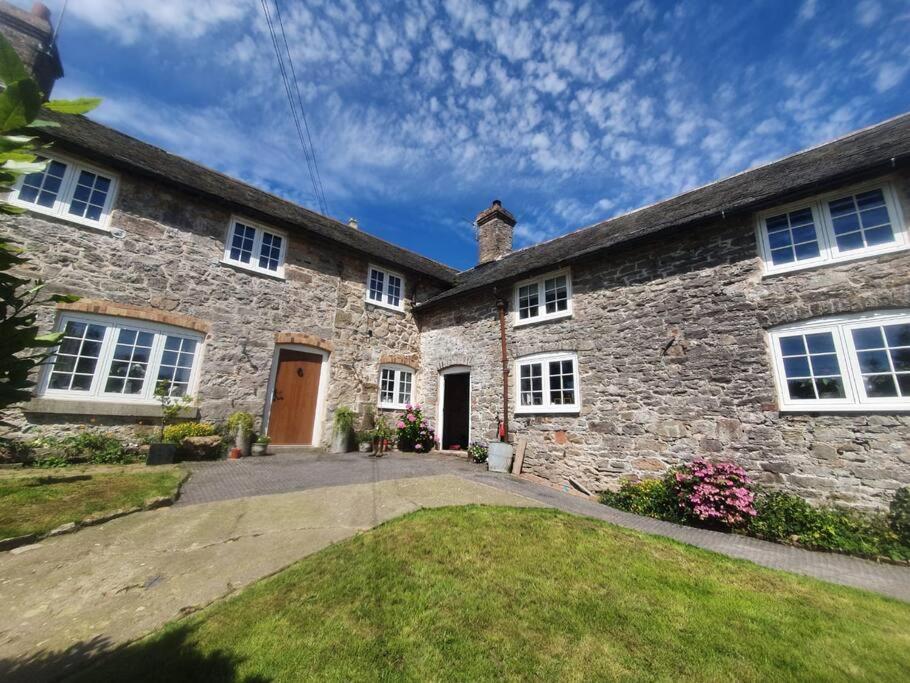 una gran casa de piedra con una entrada delante de ella en Farmhouse Cottage set in beautiful countryside, en Oswestry