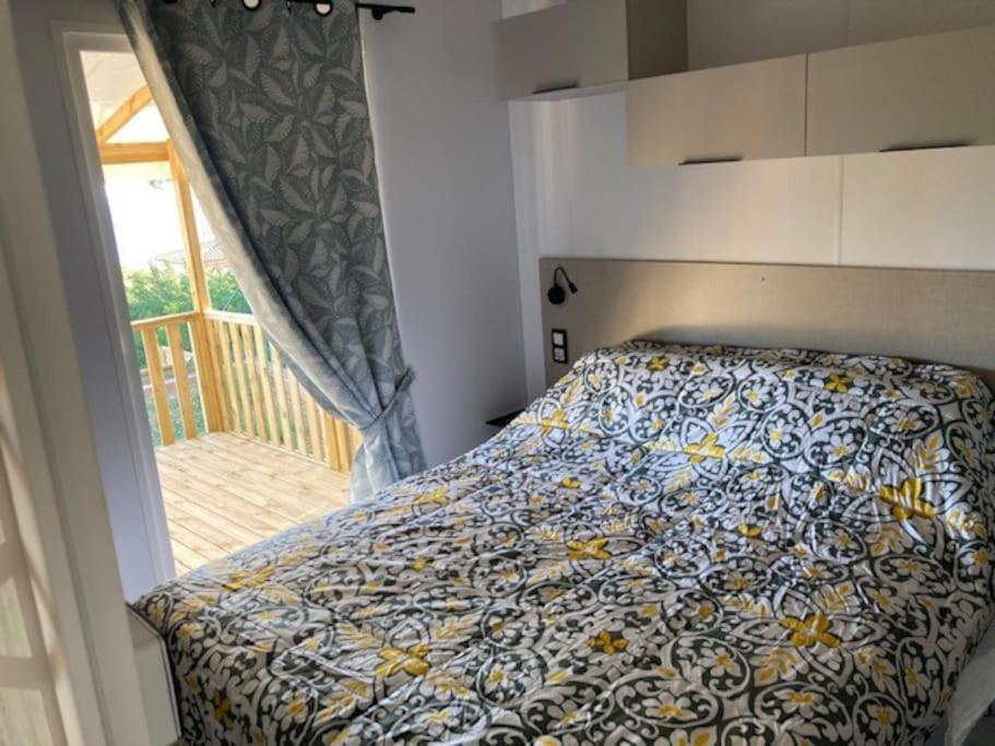 a bedroom with a bed with a flowered comforter and a window at Camping L'ILE D'OR in Saint-Raphaël