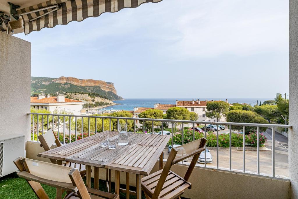 a wooden table on a balcony with a view of the ocean at Chez Jacques par Dodo-a-Cassis in Cassis