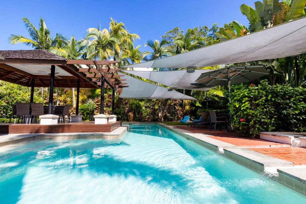 a swimming pool with umbrellas and a patio with a swimming pool at The Mediterranean Port Douglas in Port Douglas