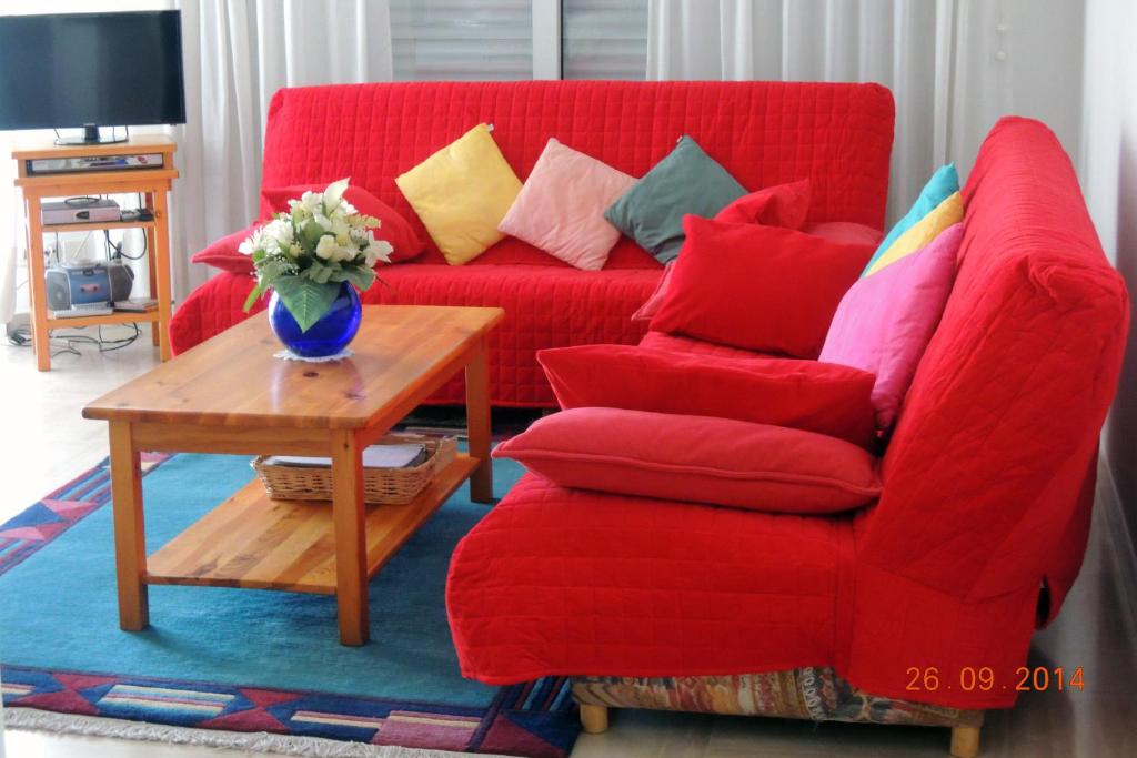 a red couch with colorful pillows and a table at Les Pins Bleus - Antibes Juan Les Pins in Juan-les-Pins