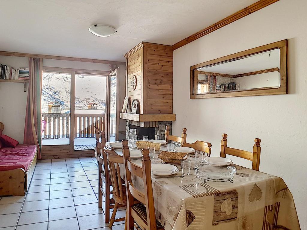 une salle à manger avec une table, des chaises et une cheminée dans l'établissement Appartement spacieux, ski aux pieds, terrasse ensoleillée et parking privé - FR-1-344-886, aux Menuires