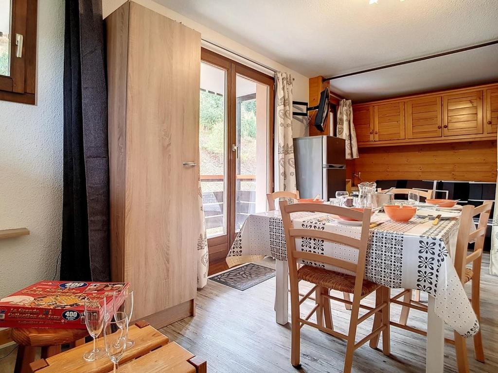 une cuisine avec une table et des chaises dans une pièce dans l'établissement Appartement confortable Proche des pistes Balcon Casier à skis - FR-1-344-916, aux Menuires