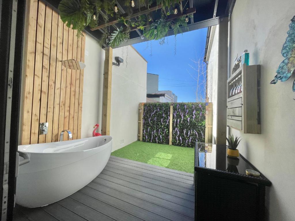 a bathroom with a tub and a large window at Coastline Retreats - Brand New Jungle Themed Garden Apartment - Outdoor Bath - Next to Seafront - Childrens Toys - Superfast Wifi - Netflix - Disney in Southbourne