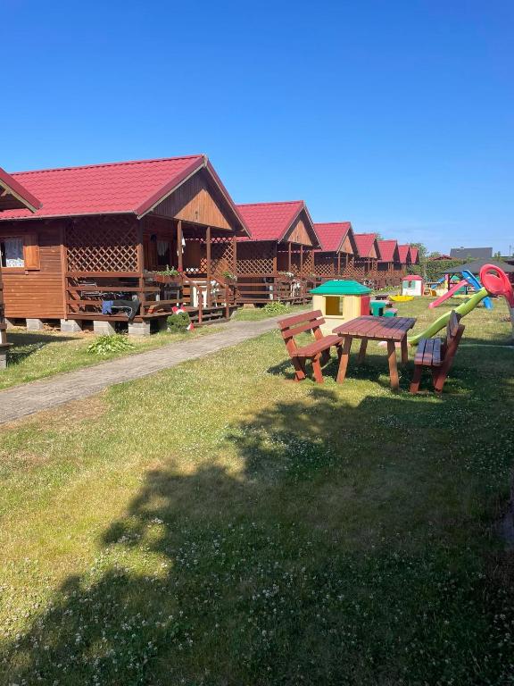 a picnic table in the grass in front of a lodge at Domki u Karasia in Rusinowo