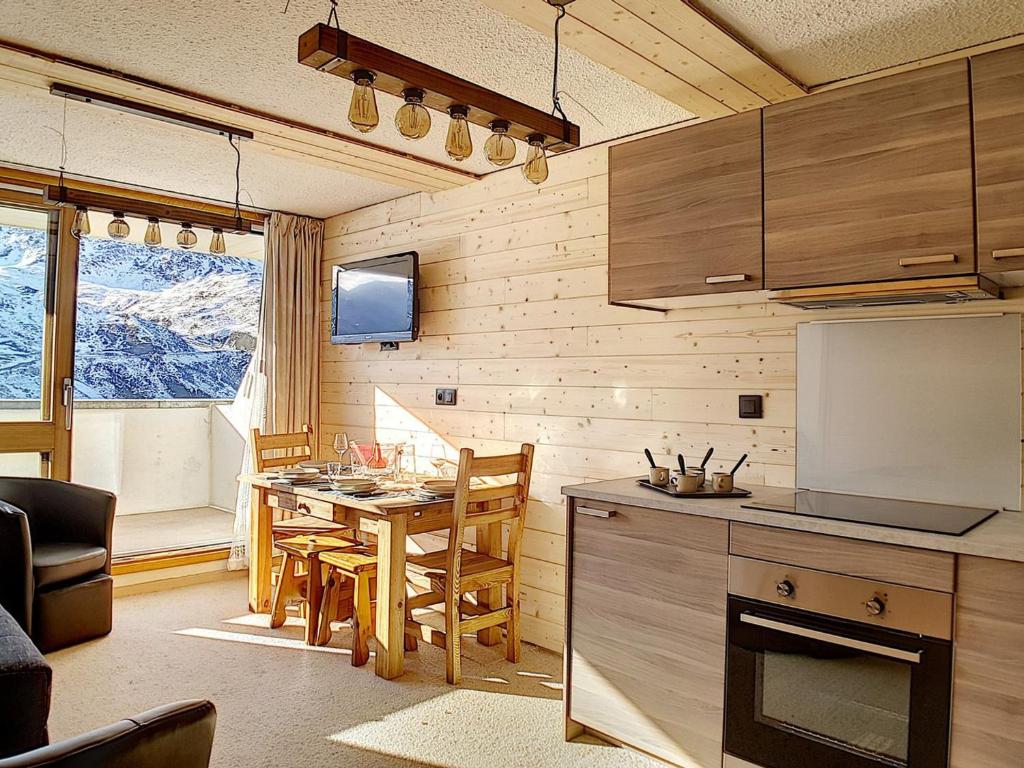 une cuisine et une salle à manger avec une table et une télévision dans l'établissement Studio Rénové au Pied des Pistes avec Balcon et Wifi - FR-1-344-949, aux Menuires