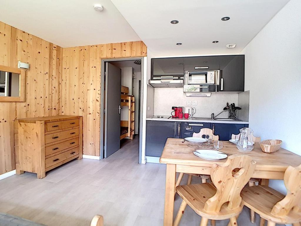 a kitchen with a wooden table and wooden chairs at Studio rénové proche pistes avec balcon, 3 couchages - FR-1-344-948 in Les Menuires