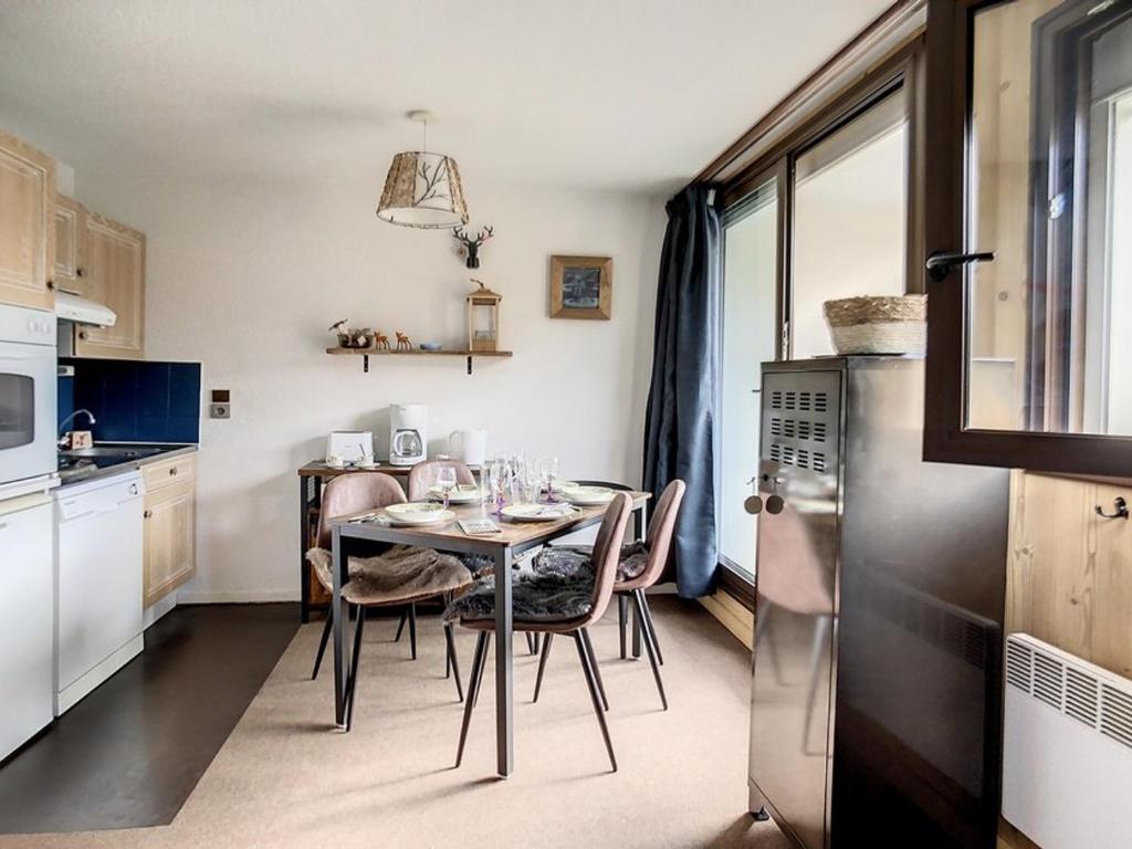 uma cozinha com uma mesa com cadeiras e um frigorífico em Studio Les Menuires, 1 pièce, 4 personnes - FR-1-344-985 em Les Menuires