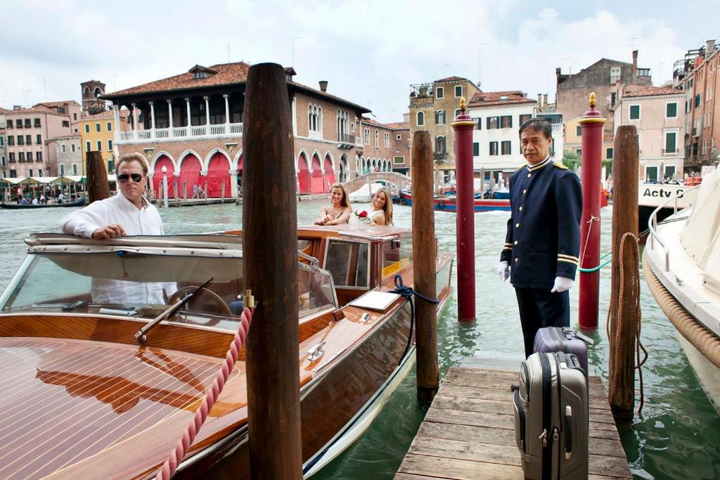 two men are standing on a boat at a dock at Pesaro Palace in Venice