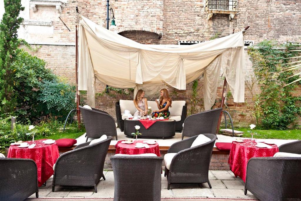 two women sitting in a gazebo with tables and chairs at Pesaro Palace in Venice
