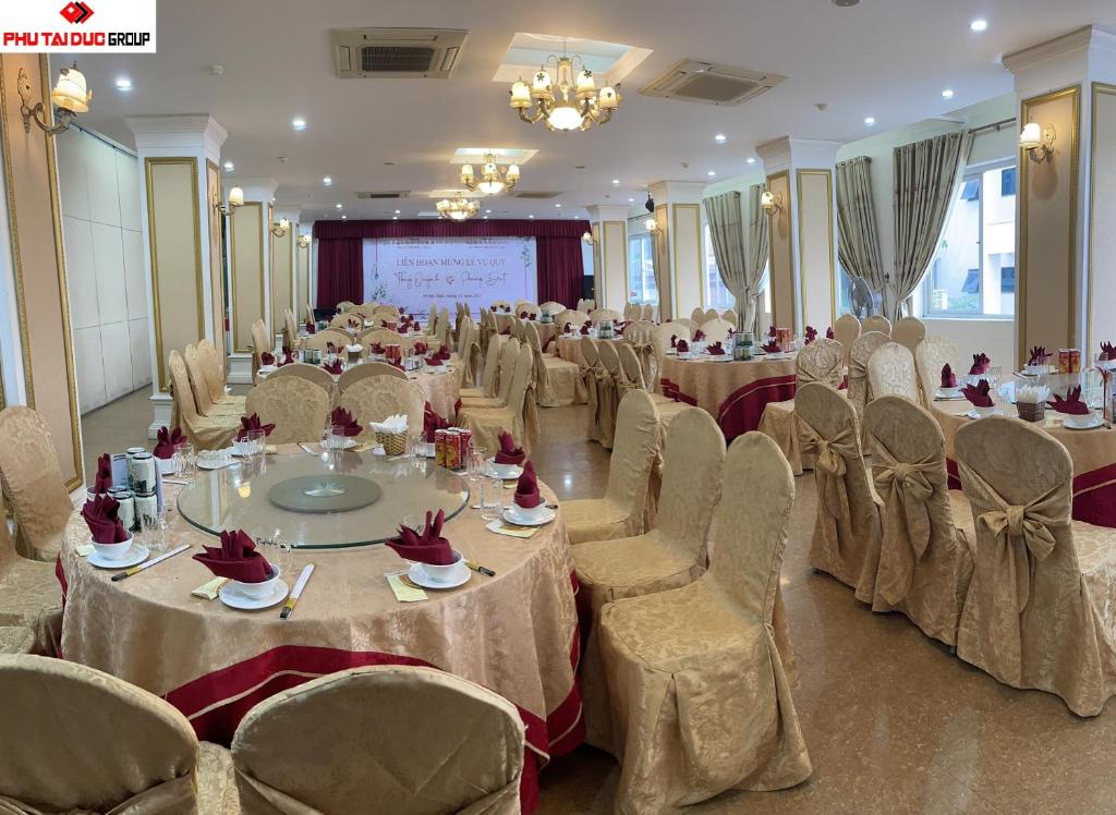 a banquet hall with tables and chairs and a screen at White Hotel in Hà Tĩnh