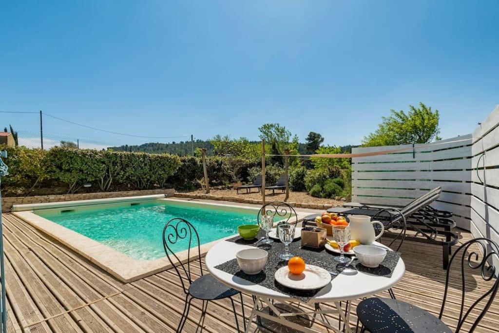 un patio con mesa y sillas junto a una piscina en Villa Syrah avec piscine privée chauffée à 25 km de la mer, en Coustouge