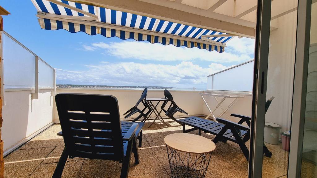 a balcony with chairs and a table and an umbrella at Appartements front de mer Royan in Royan