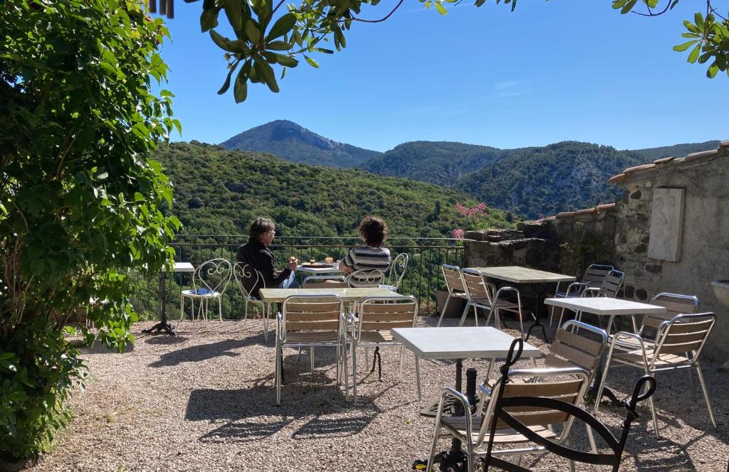 zwei Personen sitzen an Tischen mit Bergen im Hintergrund in der Unterkunft EVEN Bistrot in Évenos