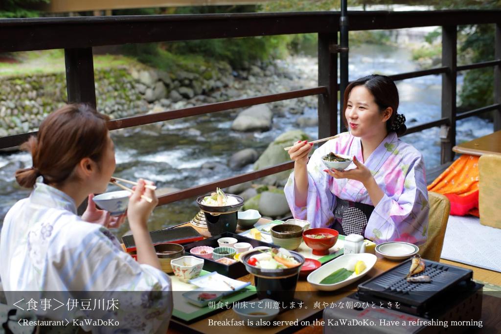 Um par de pessoas sentadas à mesa a comer. em Tatsuta Ryokan em Izu
