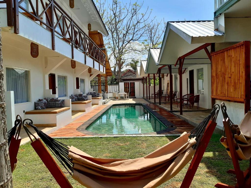 a hammock in front of a house with a pool at Katara Gili, Boutique Rooms and Bungalows in Gili Trawangan