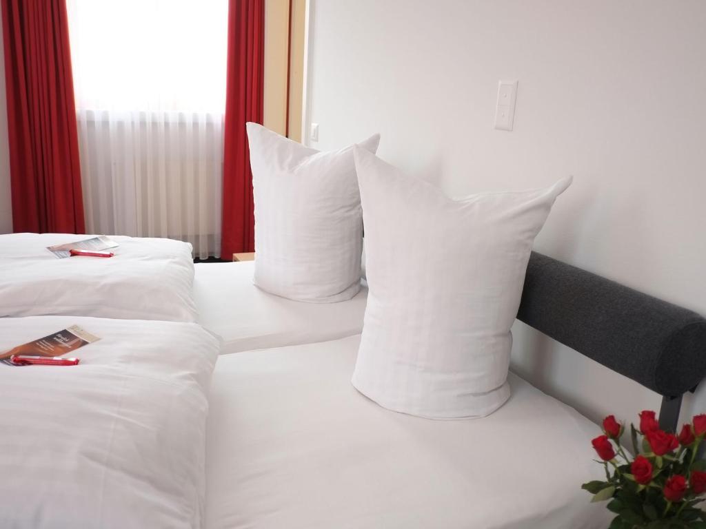 un letto bianco con cuscini e telecomando di Hotel Brauerei Frohsinn ad Arbon