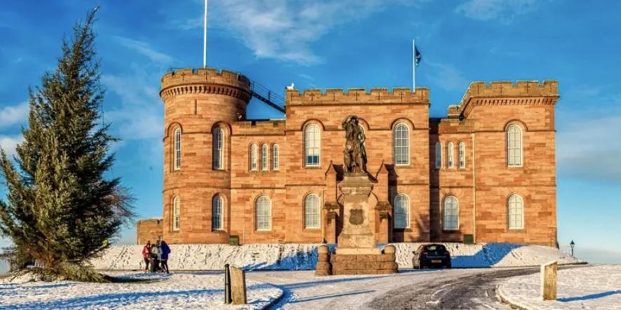 a large brick building with a statue in front at The Castle Front Nest in Inverness