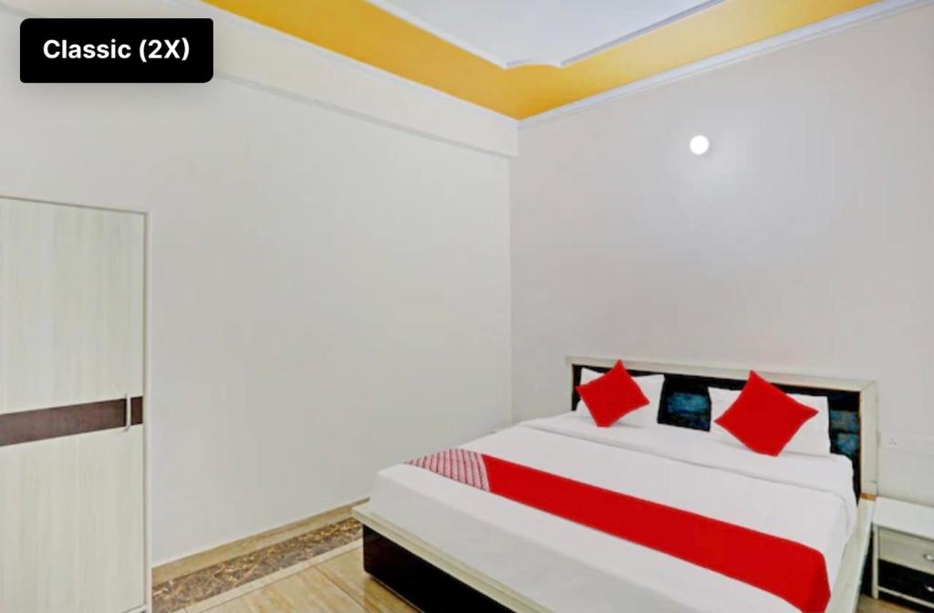 1 dormitorio con 1 cama blanca grande con almohadas rojas en Hotel NK guesthouse en Sikandra