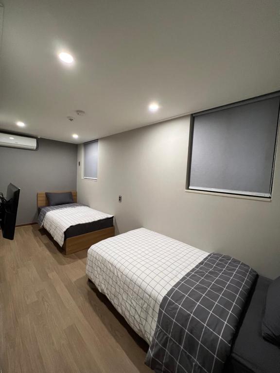 um quarto com duas camas e um ecrã de projecção em Hao Guesthouse in Hongdae em Seul