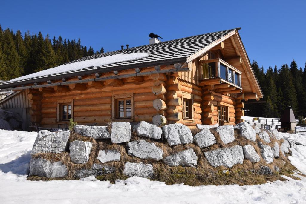 a log cabin in the snow with a stone wall at Schönberghütte in Lachtal