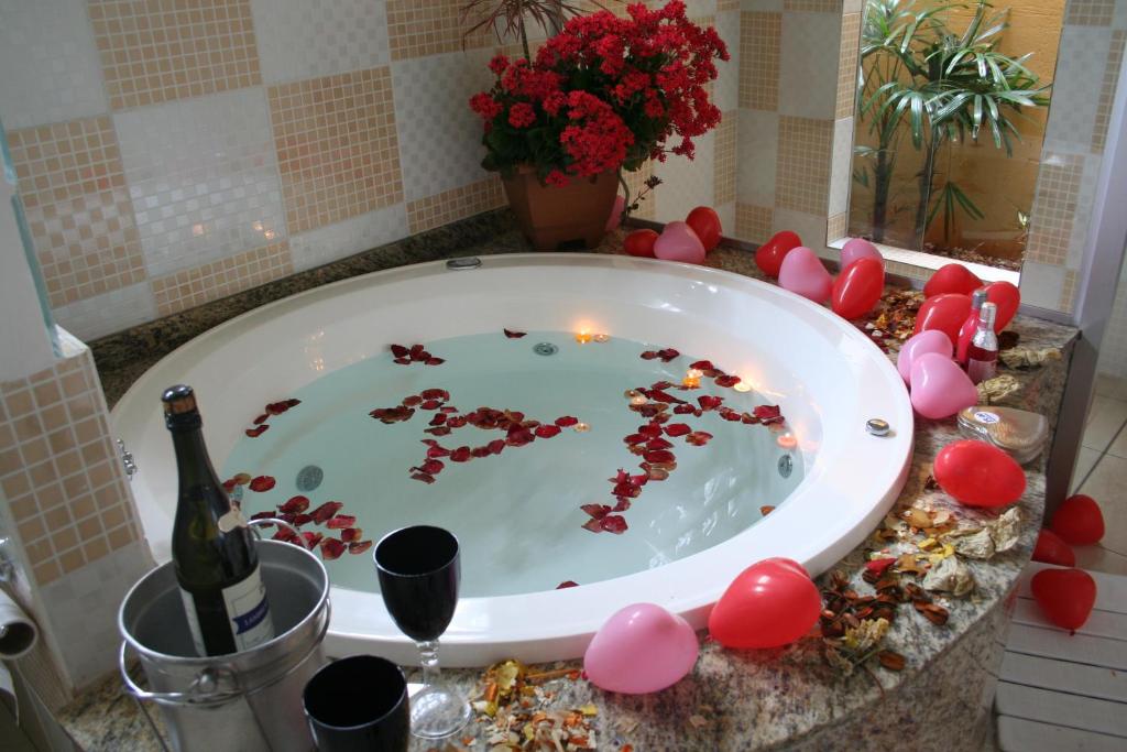 - une baignoire avec une bouteille de champagne et des ballons roses dans l'établissement Pousada das Nascentes - Brotas, à Brotas