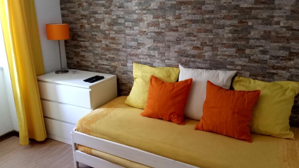 ein Schlafzimmer mit einem Bett mit orangefarbenen und gelben Kissen in der Unterkunft Casa do Pelourinho - T0 in Loriga